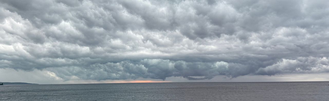 A shelf of storm cloud over open Lake Superior, with a thin orange band on the horizon